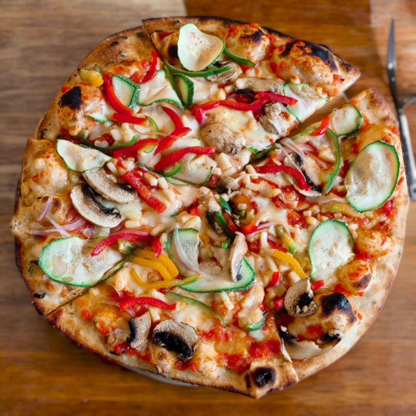 "Pizza campestre con masa artesanal cubierta de vegetales frescos como calabacín, pimientos rojos y amarillos, champiñones y cebolla, servida sobre una base de salsa de tomate."