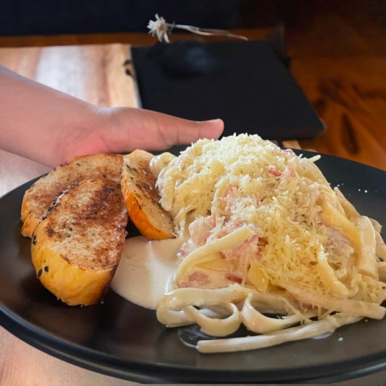 "Pasta carbonara con tocino crujiente y queso parmesano."